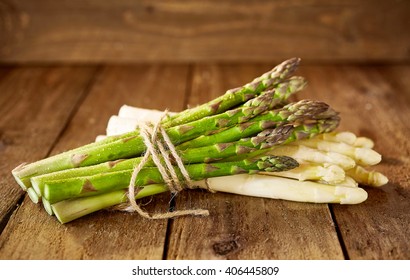 Bundles of white and green asparagus spears tied with string stacked on top of each other in wooden crate