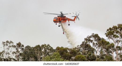 Bundoora, Australia - December 30, 2019: Erickson Air Crane Helicopter (Sikorsky S-64) N243AC Dropping A Large Load Of Water Onto A Bushfire In Support Of Fire Fighting Efforts By Crews On The Ground.