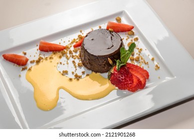 Bunet pudding,traditional italian Piedmont dessert in white plate with strawberries and eggnog 