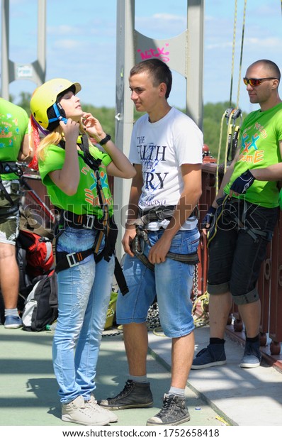 Bungee\
jumping. Worker attaching rigging to the young girl before jumping\
from a bridge. June 10, 2019. Kiev,\
Ukraine