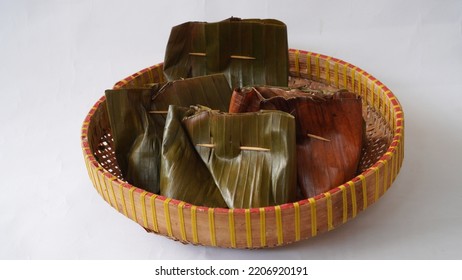 Bungkus Pisang - Banana Wrap. Traditional Wrap Method Using Banana Leaves, Sealed With A Stick. Placed On Plate Made Of Bamboo. Eye Level View