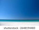 Bunker Bay Western Australia. Beautiful beach with woman in blue top and white pants walking. Deep blue sky, white sands and aqua water. No other people around. Peaceful and tranquil.