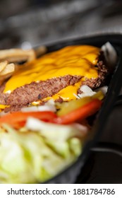 Bunless Triple Burger Meat Patties With Cheese Next To Shredded Lettuce, Sliced Tomatoes, Pickle Chips, And French Fries