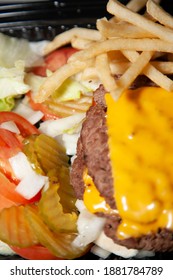 Bunless Triple Burger Meat Patties With Cheese Next To Shredded Lettuce, Sliced Tomatoes, Pickle Chips, And French Fries