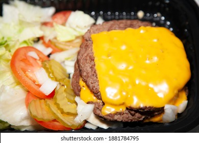 Bunless Triple Burger Meat Patties With Cheese Next To Shredded Lettuce, Sliced Tomatoes, And Pickle Chips