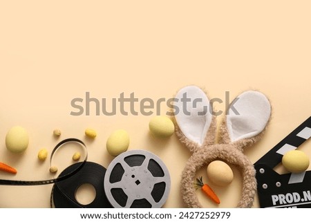 Bunny ears with Easter eggs, movie clapper and reel on beige background