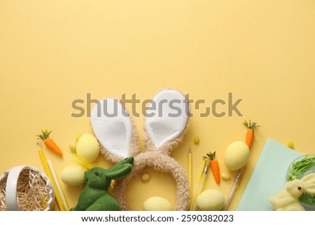 Bunny ears with Easter eggs and school supplies on yellow background