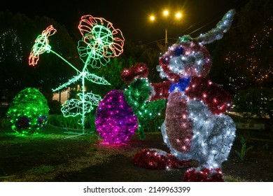 Bunny made of tinsel and garlands in the dark of the night. Easter symbol. Urban scenery during the celebration. Background with copy space