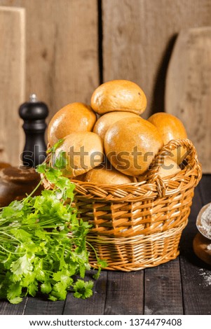 buns, croutons, pastries, in a wooden basket with fresh green leaves, lying on an old wooden sliced vintage rustic plank top, side, bottom shooting angle