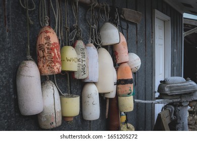 Buoys And An Old Boat Motor On The Side Of A Building.