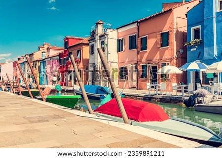 Burano, Italy with colorful painted houses along canal with boats. Scenic Italian town near Venice