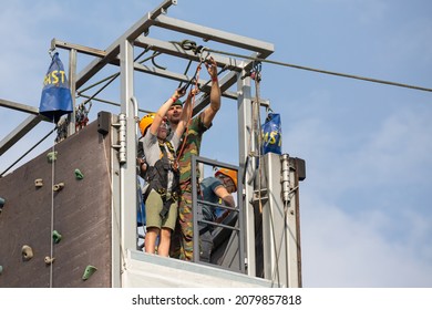 Burcht, Antwerp, Belgium 26 September 2021 : Soldier Helping Boy On Line For Rappel Abseiling On Top Of A Climbing Wall During Belgian Military Demonstration In Burcht Antwerp