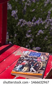 Burdur / Turkey - July 7, 2019 ; Book Concept For School. The Woman Reading Charles Dickens,A Tale Of Two Cities Book And Fan On The Red Wooden Table At The Lavender Field.