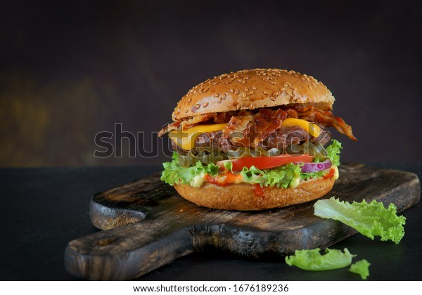 Burger with\
bacon and cheese on a dark\
background