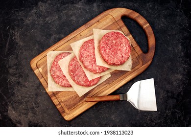 Burger BBQ Patties Top View On Wood Board And Black Background. Home Made Minced Beef Round Steak Burgers On Wooden Board. Raw Ground Beef Meat Burger Cutlets On Black Background, Overhead View.