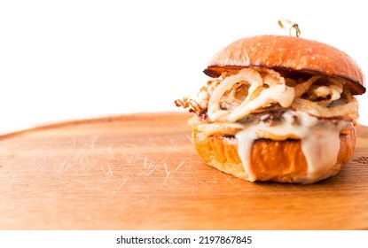 Burger With Beef Cutlet Under Tender Cream Cheese With Champignons And Onion Chips On A Wooden Plate On A White Background. Horizontal Photo