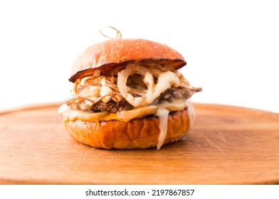 Burger With Beef Cutlet Under Tender Cream Cheese With Champignons And Onion Chips On A Wooden Plate On A White Background. Horizontal Photo