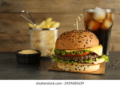 Burger with delicious patty, soda drink, french fries and sauce on gray table - Powered by Shutterstock