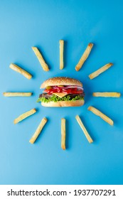 Burger with french fries laid out around on blue backdrop. Creative colorful burger - Shutterstock ID 1937707291