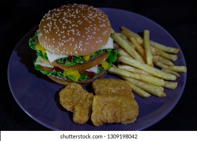 burger, french fries and nuggets on blue ratel on black wooden background