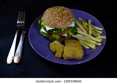 burger, french fries and nuggets on blue ratel on black wooden background