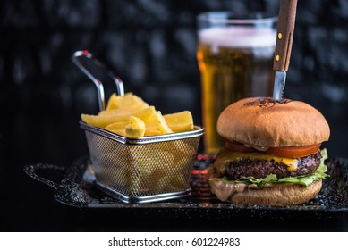 Burger, fried potatoes and beer on a dark background close-up. Street food. Fast food. - Powered by Shutterstock