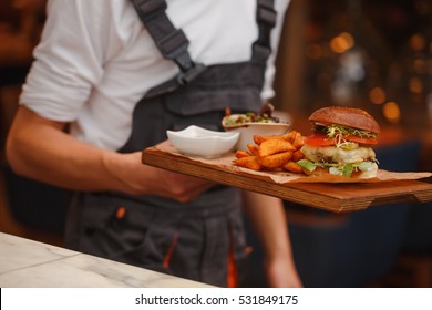 Burger with fries on waiters hands