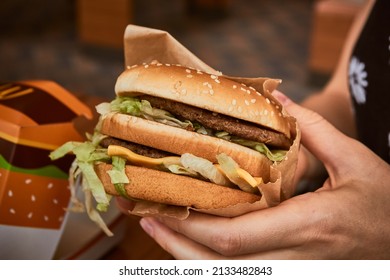 Burger in hand. Big tasty burger in the girl's hand.  - Shutterstock ID 2133482843