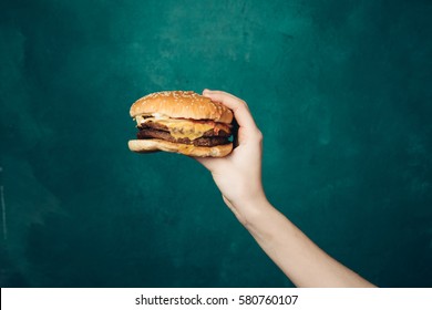 Burger in hand on bright background