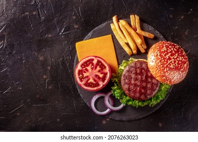 Burger Ingredients, Shot From Above On Black With Copy Space. Delicious Beef Patty Steak With French Fries And Vegetables