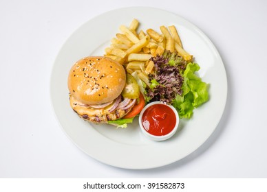 Burger With Meat Patty , Cheese , Onions, Tomatoes , Pickled Cucumbers , Green Salad , Potato Chips And Sauce . Close-up In White Plate On A White Background Top View.