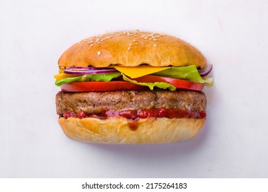 Burger with onions, ketchup, lettuce, meat cutlet, tomatoes and cheese on a white background. Horizontal orientation - Powered by Shutterstock