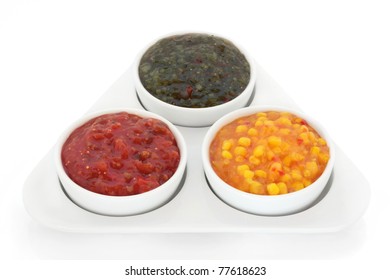 Burger Relish Selection Of Red Tomato, Green Gherkin And Sweetcorn In A Triangular Porcelain Dish With Bowls, Isolated Over White Background.