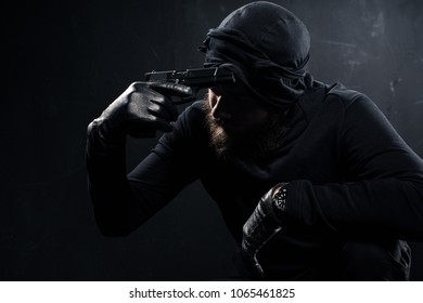 Burglar in balaclava scratching his head with gun - Shutterstock ID 1065461825