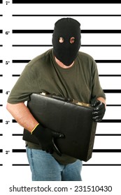 A Burglar in a Black Ski Mask, with Black Gloves is booked by the Police and his Mug Shot aka MUGSHOT taken. Bad Guys who get caught get mug shots. Holding his stolen property in the photo. Bad man