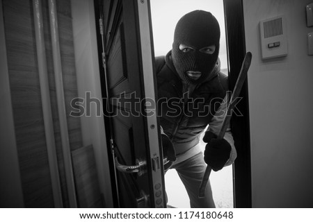 
Burglar breaking door of house with crowbar