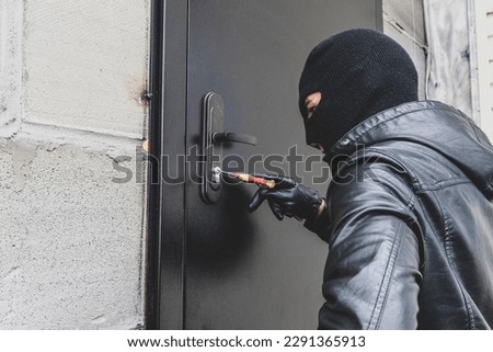 Burglar breaking into house. A burglar opens the lock on the iron door of a country house. A criminal concept. Burglary.