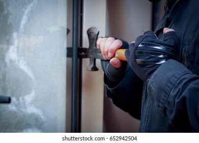 Burglar with crowbar to break door to enter the house - Shutterstock ID 652942504