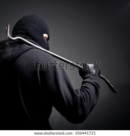 A burglar with a crowbar on the shoulder. View from the back