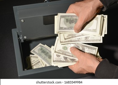 Burglar stealing money from safe box, closeup