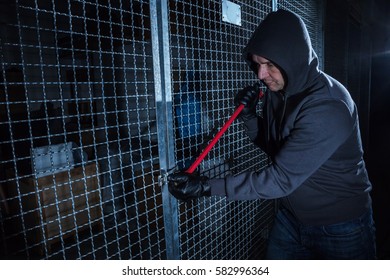 Burglar Trying To Break The Gate Of Storage Room With A Crowbar