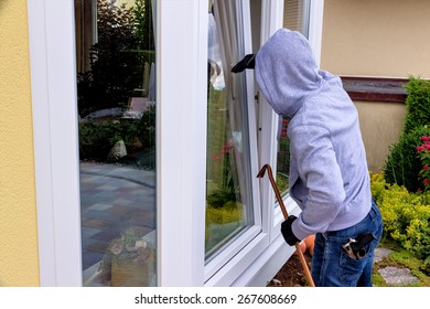 a burglar trying to break in an open window with a crowbar