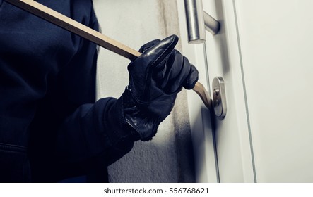 Burglar Using Crowbar To Break A Home Door At Night