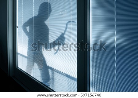 Burglar wearing a balaclava looking through the house window