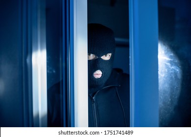 Burglary Concept. Evil Thief Looking At Camera Through Open Front Door, Entering Enclosed Property