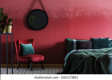 Burgundy Bedroom Interior With Armchair And Round Mirror Hanging On The Wall