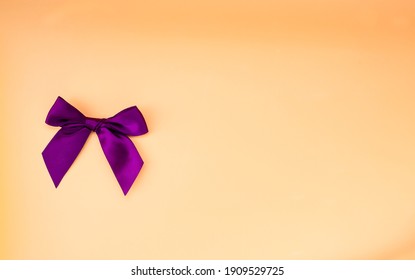 Burgundy Bow On A Orange Background. Top View