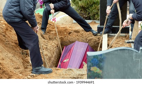 Burial. Men lower the coffin into the grave