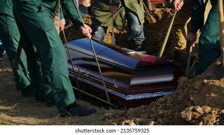 Burial. Men Lower The Coffin Into The Grave. N