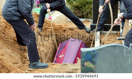 Burial. Men lower the coffin into the grave